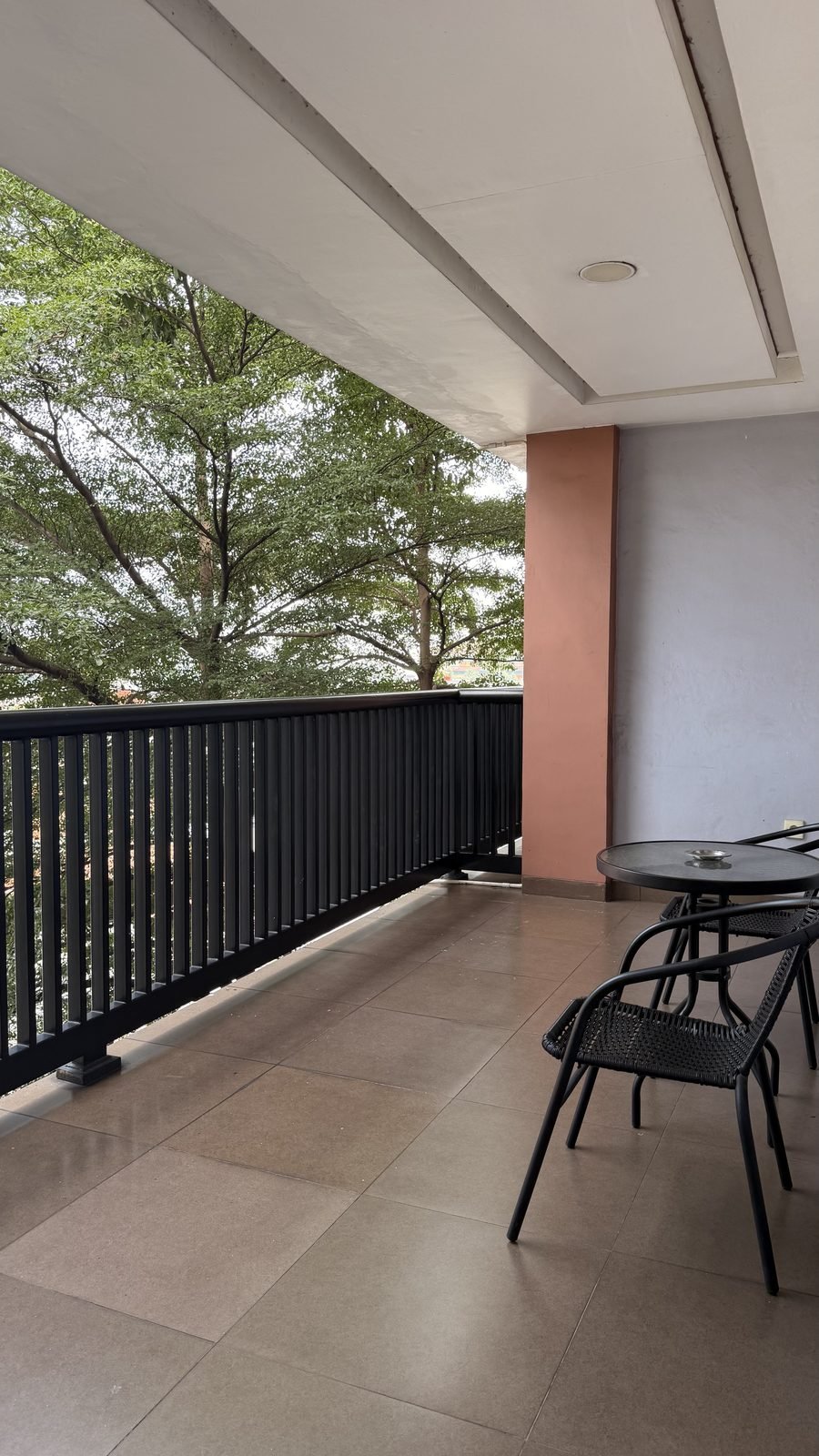 Balkon dengan kursi santai dan pepohonan rindang